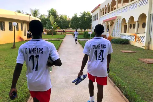 Deux joueurs vêtus de maillot blanc, short rouges marchent en direction du terrain.